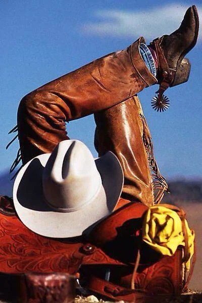 Brown leather boots, a white hat, and a patterned red outfit beneath a blue sky.
